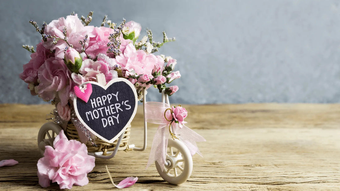 Pink floral arrangement in a miniature bicycle basket with a “Happy Mother’s Day” sign.