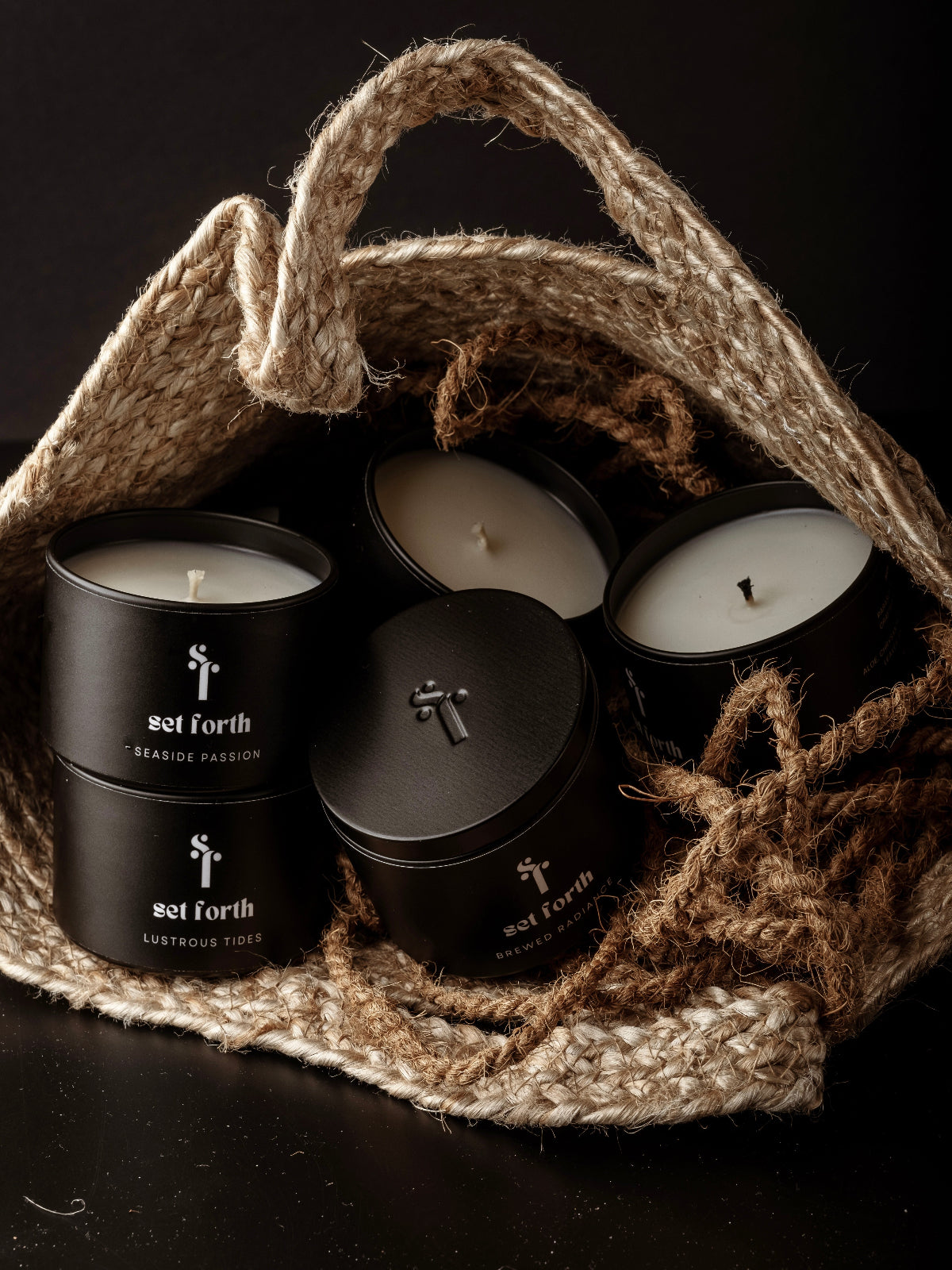 Set Forth NY candles in matte black tins styled inside a rope bag for the homepage banner.