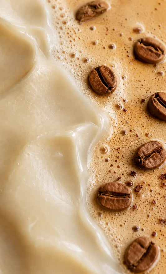Coffee beans resting on creamy coffee foam